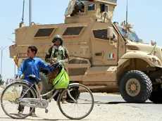 Un bambino in bicicletta davanti a un soldato e a un blindato italiani in Afghanistan