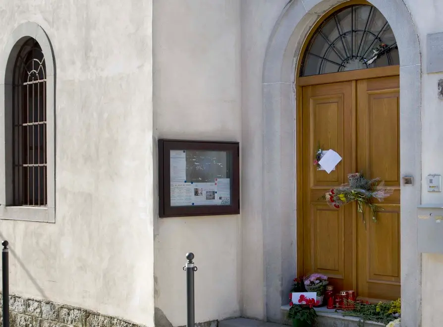 Fiori, lumini, messaggi davanti al portone della casa parrocchiale in memoria di don Suard (Silvano)