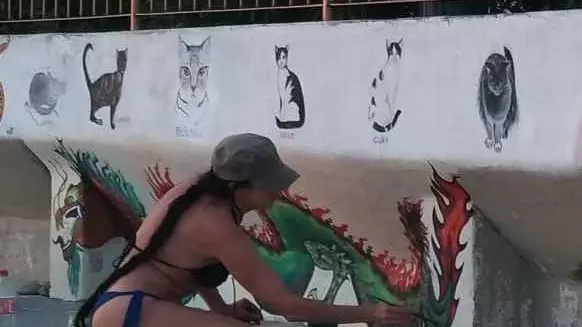 Rossana Romano mentre dipinge creature marine sui muri dell’ex Cedas a Barcola