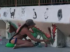Rossana Romano mentre dipinge creature marine sui muri dell’ex Cedas a Barcola