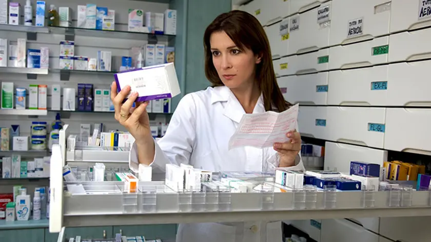 Beautiful female model pharmacist looking at medicine