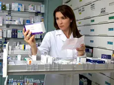 Beautiful female model pharmacist looking at medicine