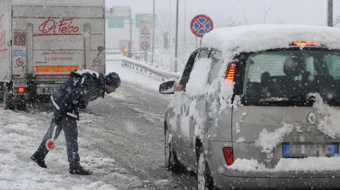 Agenti della polizia all'ingresso per l'autostrada A24 per Roma controllano che i veicoli siano dotati di pneumatici da neve o catene, Chieti, 3 febbraio 2012. ANSA / MASSIMILIANO SCHIAZZA