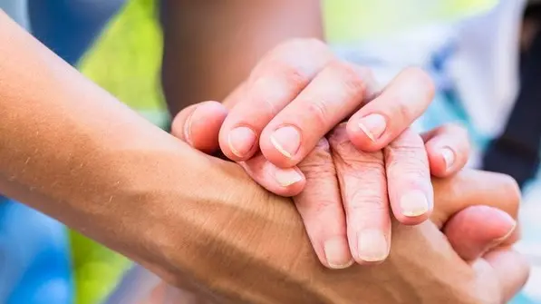 Nurse consoling senior woman holding her hand