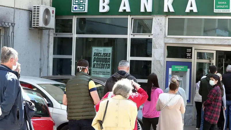 epa08387153 People wearing protective face masks queue in front of a bank office in Sarajevo, Bosnia and Herzegovina, 27 April 2020, amid the ongoing coronavirus COVID-19 pandemic. Countries around the world are taking increased measures to stem the widespread of the SARS-CoV-2 coronavirus which causes the COVID-19 disease. EPA/FEHIM DEMIR