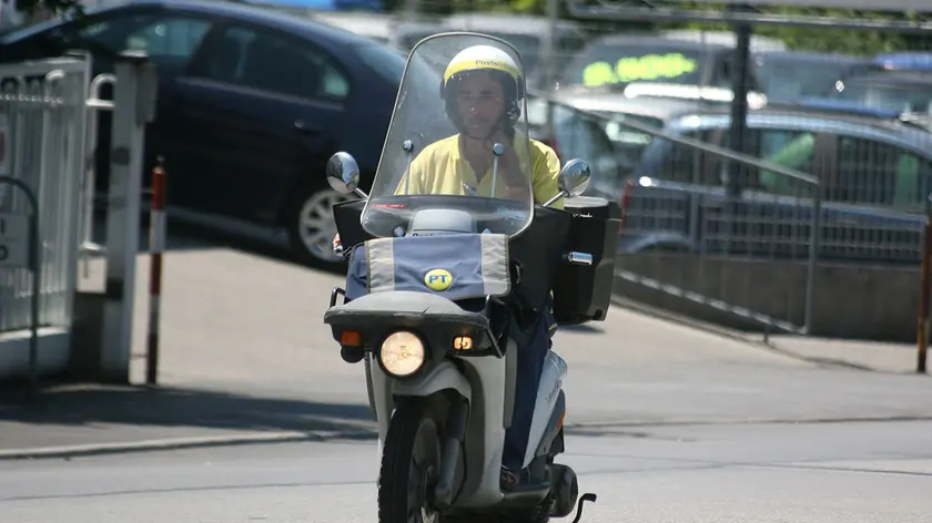 Un postino in sella a uno scooter in un'immagine di archivio