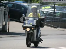 Un postino in sella a uno scooter in un'immagine di archivio