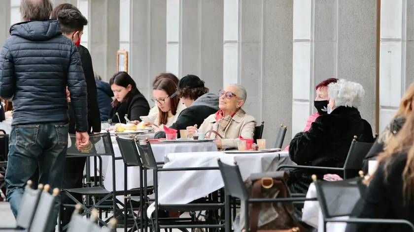 Primo giorno in zona gialla nella foto di Massimo Silvano: pochi i tavolini dei bar riempiti a causa della bora