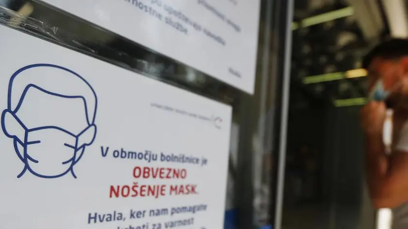 A sinistra cartello all’ingresso di un grande magazzino a Lubiana con l’obbligo di indossare le mascherine