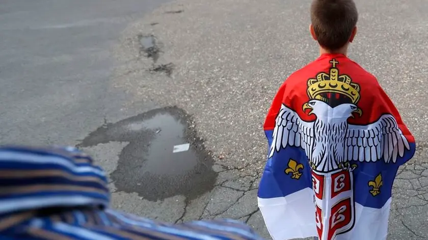 A boy with an old Montenegro flag attends during a protest after arrest of the Serbian Orthodox Church priests in Montenegro, in Belgrade, Serbia, Thursday, May 14, 2020. Montenegrin police said Thursday they have detained around 60 people following clashes at protests demanding the release of eight Serbian Orthodox Church priests jailed for leading a religious procession despite a ban on gatherings related to the new coronavirus outbreak. (AP Photo/Darko Vojinovic)