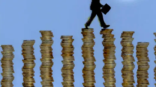Businessman walking across stacks of coins forming money bar chart