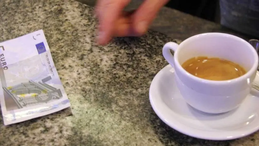 Un cliente paga un caffè ordinato al banco di un bar