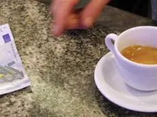 Un cliente paga un caffè ordinato al banco di un bar