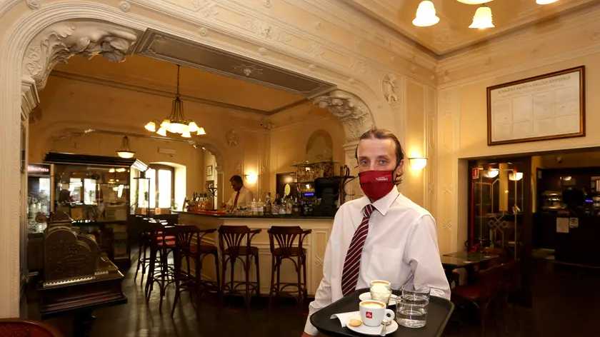 Un cameriere al lavoro dentro il Caffè Tommaseo che da lunedì 19 chiuderà fino a settembre. Foto Lasorte