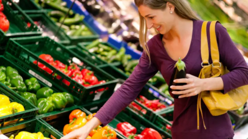 Una ragazza sceglie frutta e verdura in un supermercato