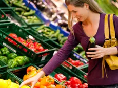 Una ragazza sceglie frutta e verdura in un supermercato