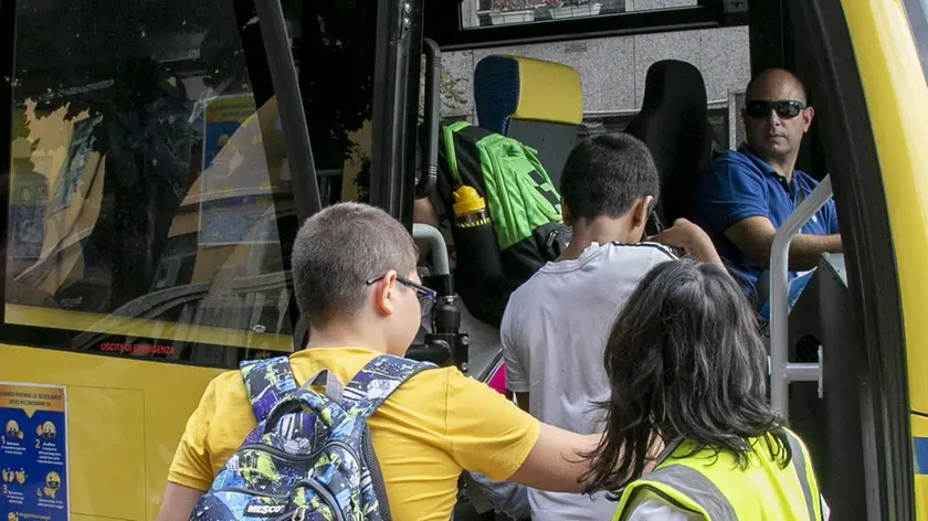 Alunni mentre salgono sullo scuolabus per raggiungere la scuola
