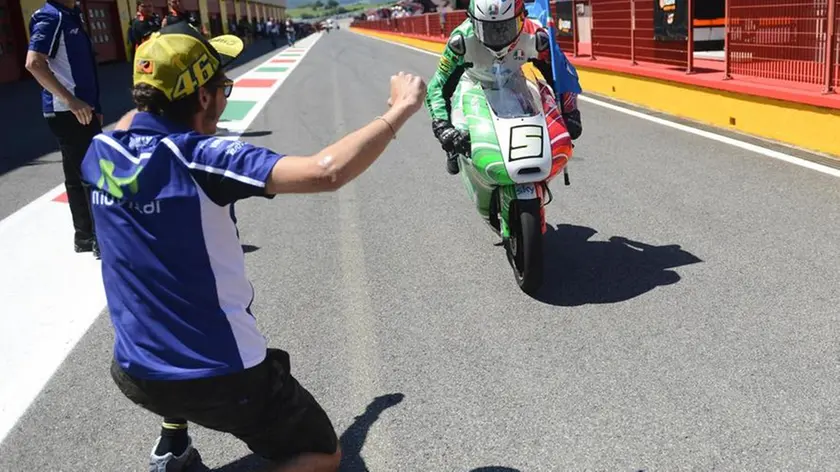 Valentino Rossi accoglie in ginocchio davanti al box il pilota italiano Romano Fenati (Ktm) che ha vinto il Gp d'Italia nella categoria della Moto3 sul circuito del Mugello, 1 giugno 2014. ANSA/UFFICIO STAMPA SKY SPORT ++ NO SALES, EDITORIAL USE ONLY ++