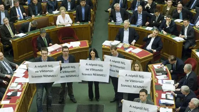 epa03619329 Members of the Parbeszed Magyarorszagert (Dialogue for Hungary) opposition party hold banners written: 'Fear the people, but do not fear Viktor! Vote NO!' prior to the voting of the modified Fourth Amendment of the Basic Law in the Parliament building in Budapest, Hungary, 11 March 2013. Behind the protesters Hungarian Prime Minister Viktor Orban (5-R, in the front row) reacts. 68,8 per cent of the Members of Parliament voted yes to the modified Basic Law. EPA/SZILARD KOSZTICSAK HUNGARY OUT