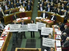 epa03619329 Members of the Parbeszed Magyarorszagert (Dialogue for Hungary) opposition party hold banners written: 'Fear the people, but do not fear Viktor! Vote NO!' prior to the voting of the modified Fourth Amendment of the Basic Law in the Parliament building in Budapest, Hungary, 11 March 2013. Behind the protesters Hungarian Prime Minister Viktor Orban (5-R, in the front row) reacts. 68,8 per cent of the Members of Parliament voted yes to the modified Basic Law. EPA/SZILARD KOSZTICSAK HUNGARY OUT