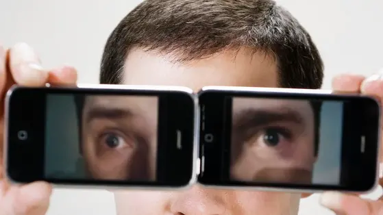 Young man using camera phones as eyeglasses --- Image by © W2 Photography/Corbis