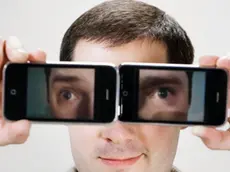 Young man using camera phones as eyeglasses --- Image by © W2 Photography/Corbis