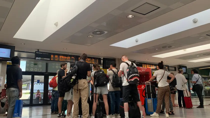 Viaggiatori in attesa delle comunicazioni sui tabelloni delle partenze