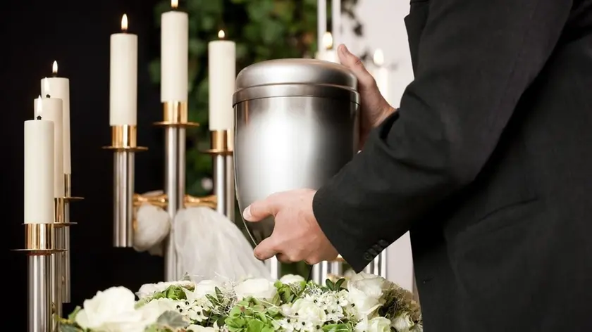 death and dolor - funeral and cemetery, mortician carrying the urn to a bed of white roses