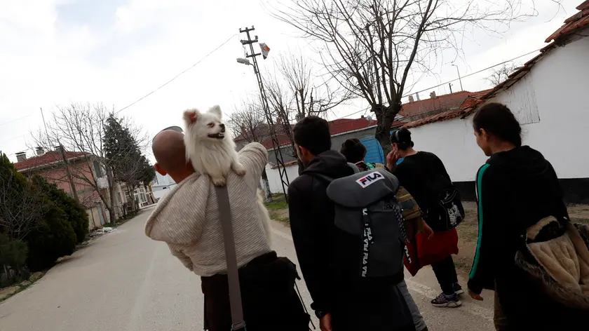 A man from Iran carries his dog as he walks with other migrants near Edirne at the Turkish-Greek border, Monday, March 9, 2020. Thousands of migrants have massed at Turkey\'s land border with EU-member Greece after Erdogan\'s government made good on a long-standing threat and announced that Turkey _ which is home to more than 3.5 million Syrian refugees _ would no longer prevent migrants and refugees from crossing over into EU countries. (AP Photo/Darko Bandic)