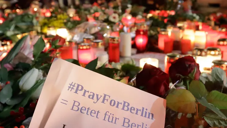 People stay in front of candles close to a Christmas market beside the memorial church in Berlin, Germany, Wednesday, Dec. 21, 2016, two days after a truck ran into a crowded Christmas market and killed several people. (AP Photo/Michael Sohn)