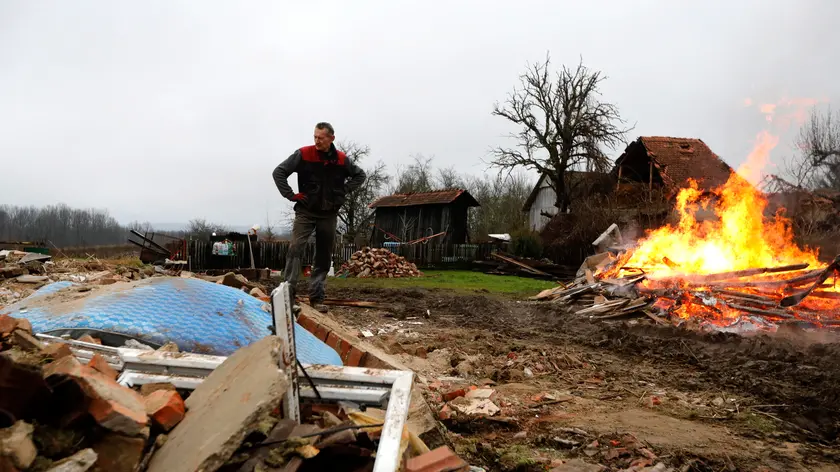 epa08918705 A man stands in front his destroyed house and burns debris in the Majske Poljane village near Glina, 04 January 2021. The 6.4 magnitude earthquake that struck Croatia on 29 December 2020 left many houses in Petrinja, Sisak and the Glina area damaged or destroyed and another 4.2 magnitude aftershock was measured earlier on 04 January 2021. The 29 December 2020 earthquake left numerous people injuried and at least seven people dead. EPA/ANTONIO BAT