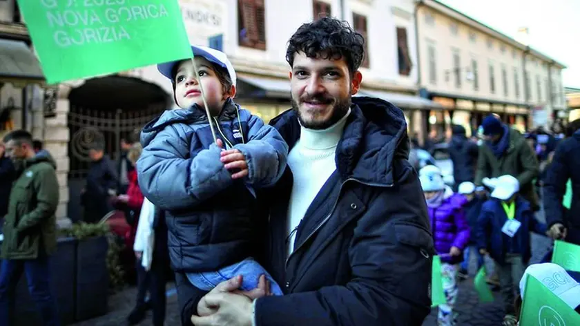 Un papà con il figliolo in braccio partecipa alla festa nelle strade di Gorizia Foto Bumbaca