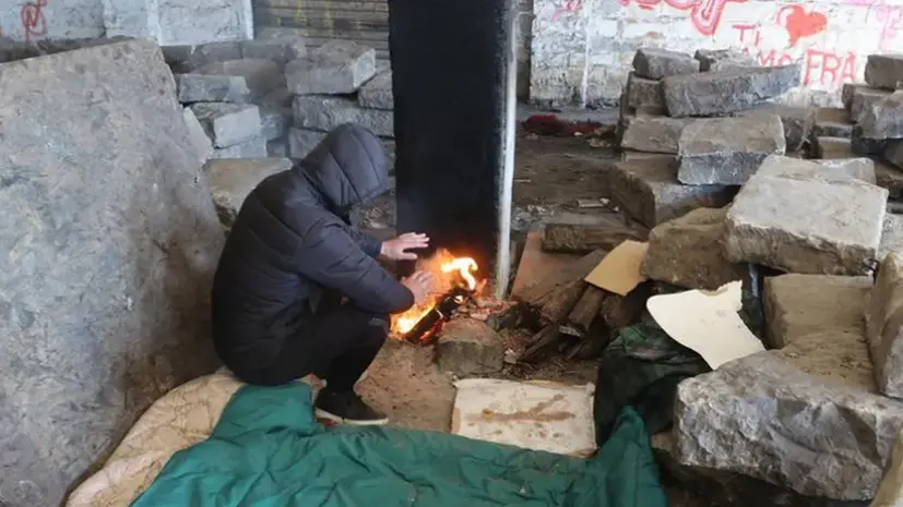 Migrante si riscalda in un magazzino di Porto Vecchio (Foto d'archivio)