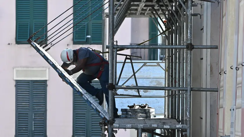 Un operaio al lavoro su un ponteggio per un intervento di riqualificazione finanziato con il Superbonus