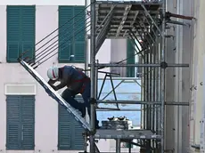Un operaio al lavoro su un ponteggio per un intervento di riqualificazione finanziato con il Superbonus