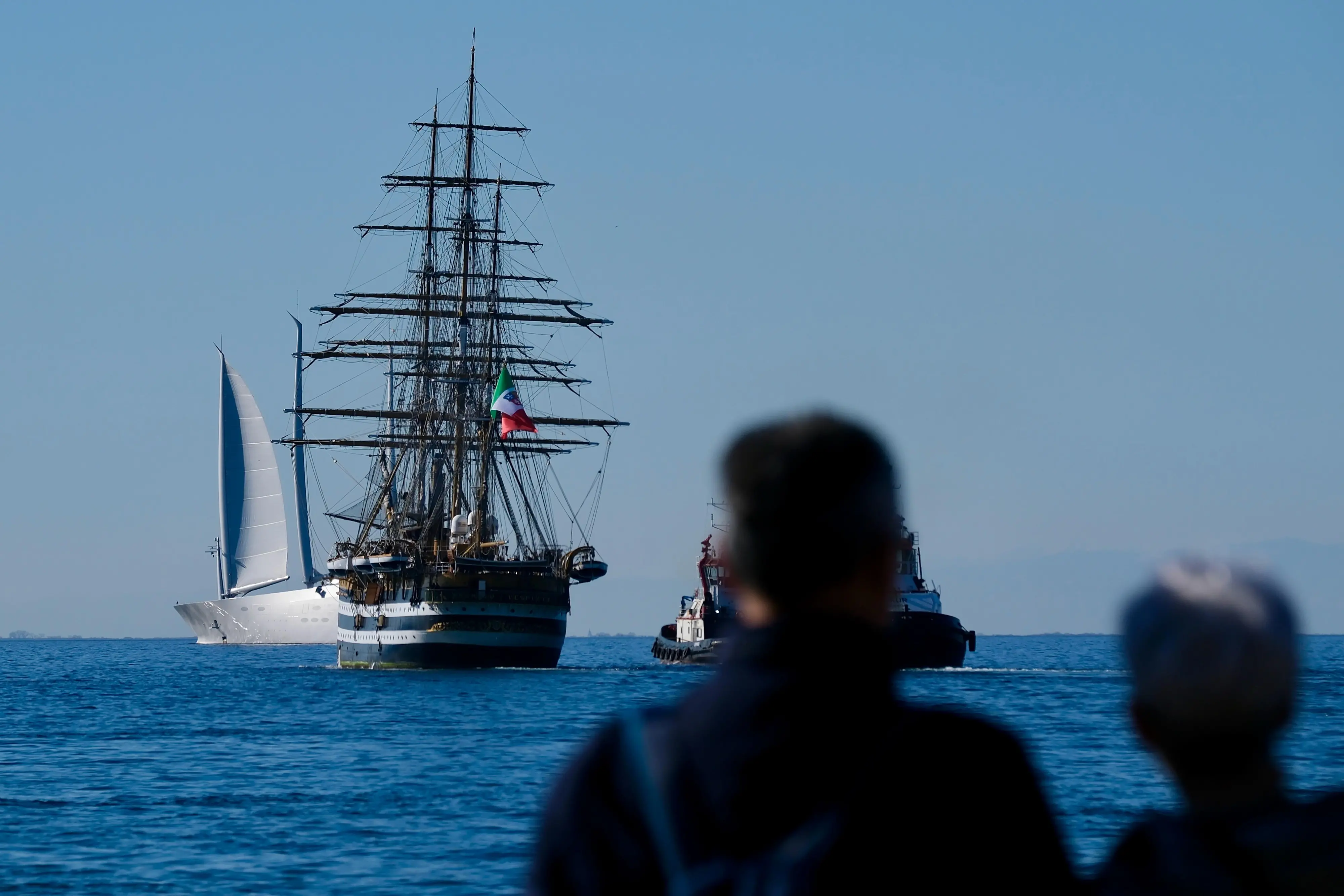 Il veliero Vespucci ha mollato gli ormeggi dalle Rive di Trieste e si è trasferita all'Arsenale del porto cittadino. Tre fischi di sirena in segno di saluto a Trieste, la città che l’ho accolto festosamente al rientro del tour mondiale. Alle 15 di martedì 4 marzo la nave scuola della Marina Militare si è allontanata dalla Riva del Mandracchio e si è lasciata alle spalle piazza Unità d’Italia, dopo tre giorni di celebrazioni. Centinaia di triestini e turisti sono accorsi sulle Rive e sul Molo Audace per salutare quella che è considerata la nave più bella del mondo. Impossibile replicare il bagno di folla che l’ha accolta domenica all’arrivo, con tanto di passaggio delle frecce tricolori. Ma in tanti hanno voluto essere presenti alla partenza. Due rimorchiatori hanno girato il vascello, con manovre morbide e precise, quasi a passo di danza. L’impressione, da terra, era di osservare un carillon silenzioso che in qualche minuto ha permesso al veliero di puntare la prua verso l’Adriatico, pronto per il tour Mediterraneo. Prima di allontanarsi, il saluto alla città. Tre fischi di sirena e i marinai che sventolano mani e cappelli. Trieste ricambia con lo stesso affetto e sulle Rive scroscia un applauso che suona come un arrivederci. Notizia di Maria Elena Pattaro foto di Massimo Silvano