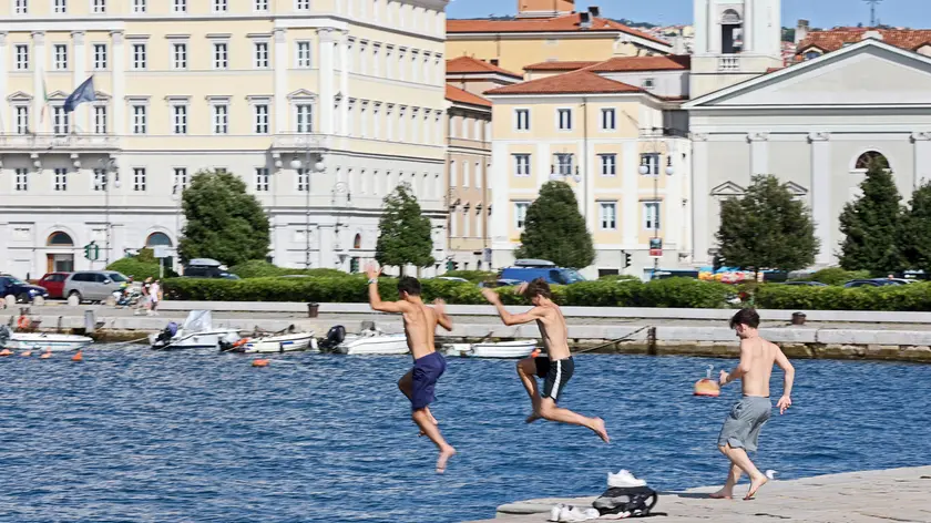 Tre ragazzi si lanciano dal molo Audace (foto Lasorte)