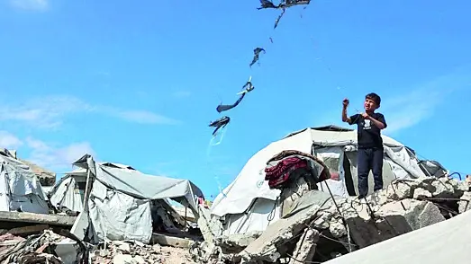 Un bambino in un campo profughi tra le rovine della Striscia di Gaza