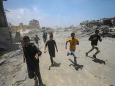 Civili corrono al riparo dopo un attacco aereo israeliano a ovest di Gaza City