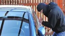 Un ladro guarda all’interno di un’auto parcheggiata ARCHIVIO