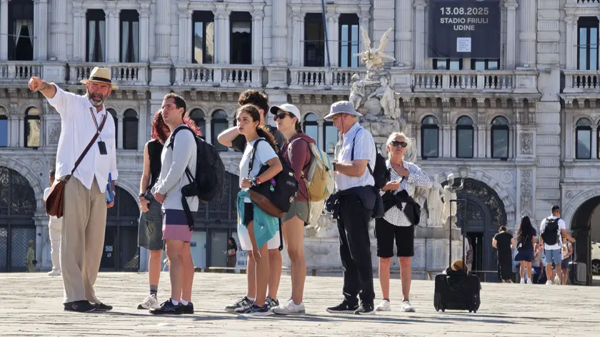 Turisti con una guida in piazza Unità d’Italia dove il 14 agosto si svolgerà lo spettacolo con i droni Foto Andrea Lasorte