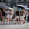 Turisti in piazza Duomo a Milano fronteggiano il caldo. Foto Ansa