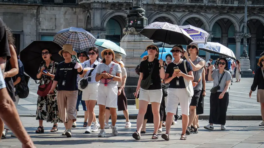 Turisti in piazza Duomo a Milano fronteggiano il caldo. Foto Ansa