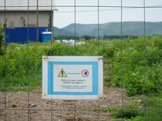 «Sono in corso lavori di bonifica amianto». Così recita un cartello in aeroporto e, sullo sfondo, si intravvedono i sacchi bianchi dove è stato riposto il materiale da rimuovere (Foto Marega).
