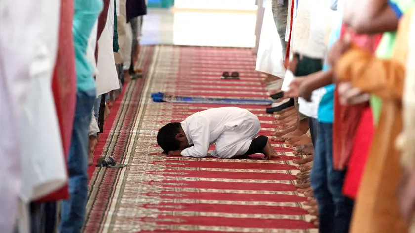 Un bambino s’inginocchia durante un momento di raccoglimento spirituale collettivo della comunità islamica foto di archivio di Katia Bonaventura