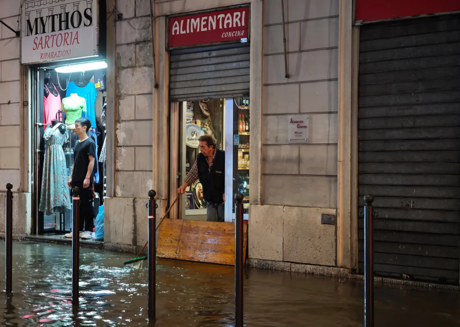 Un negoziante cerca di far defluire l'acqua