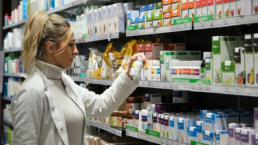 Una farmacista al lavoro tra scaffali pieni di medicinali e integratori (foto Silvano)