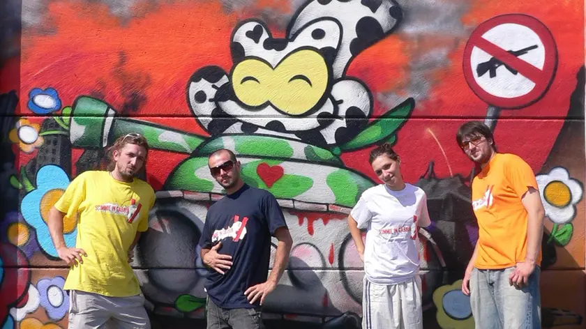 Alcuni componenti del gruppo Scimmie in gabbia davanti a murales colorati e a un concerto rap