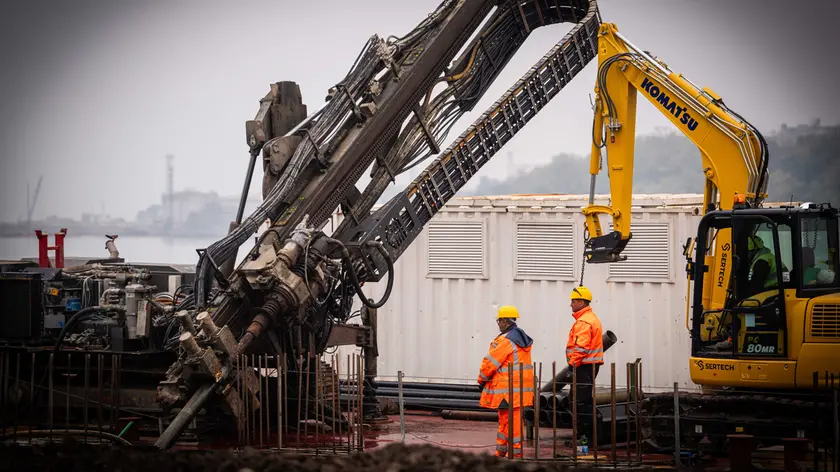 Grandi macchinari all’opera nell’area ex Aquila nel cantiere Pnrr per realizzare la banchina