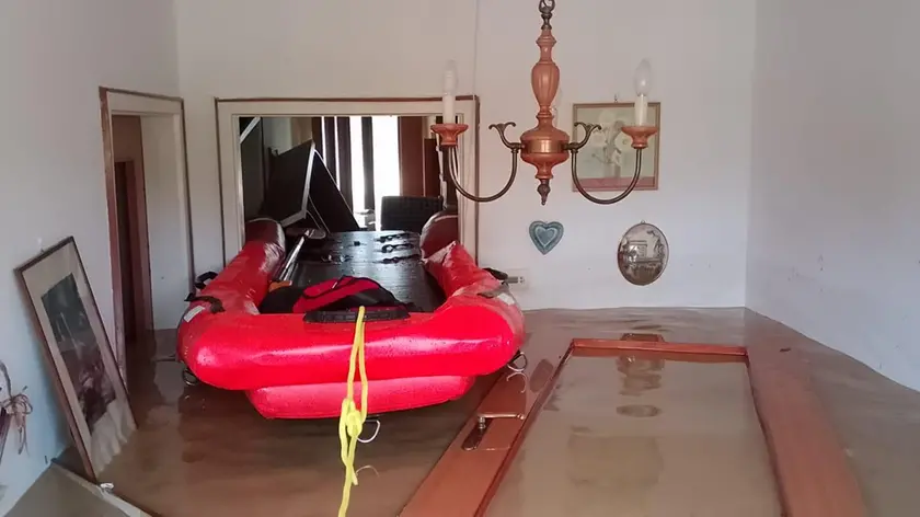 Un gommone dei soccorritori nel soggiorno di una casa allagata a Versa
